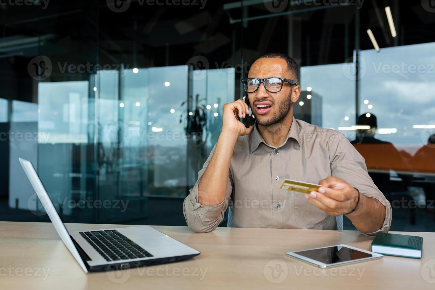 Dissatisfied businessman in the office with a bank credit card calls customer support, blocked card man can't make a purchase in an online store. photo