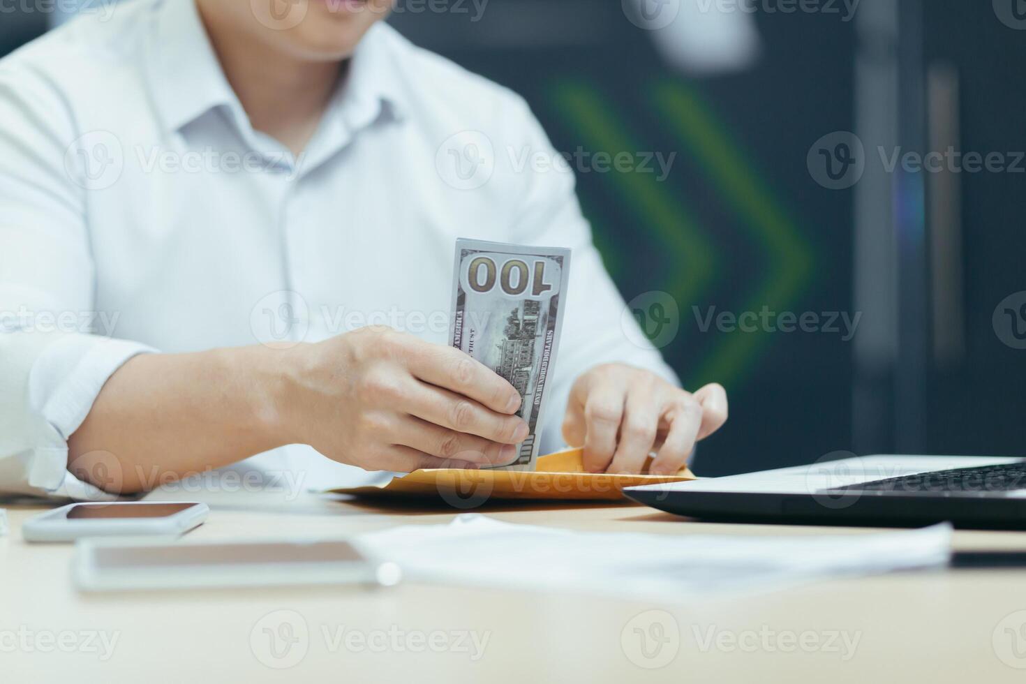 Close-up photo. Hands of a young man putting cash, dollars in a wallet, counting money in the office at the table. Financial award, bonus, salary. photo