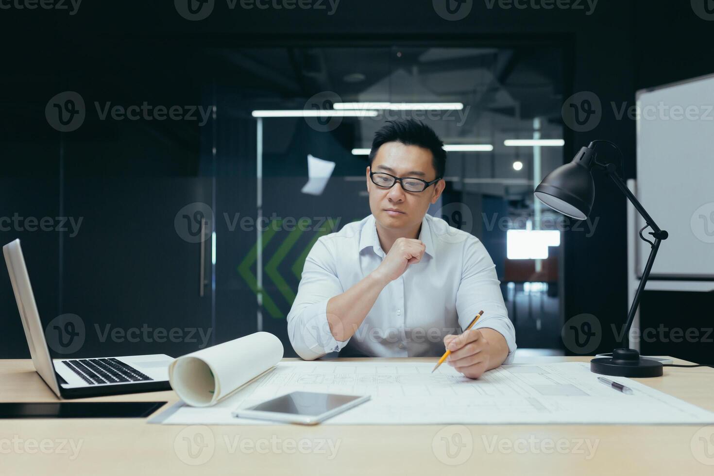 Thinking asian engineer architect working in modern design office, man looking at drawing plan. photo