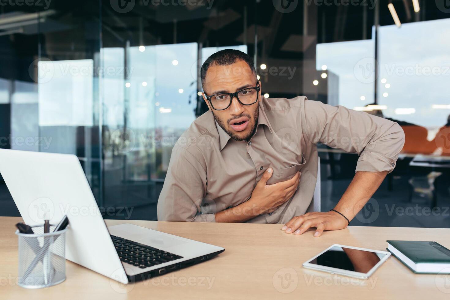 heart attack at work, businessman sick has severe chest pain heartache, african american man working inside office building using laptop. photo