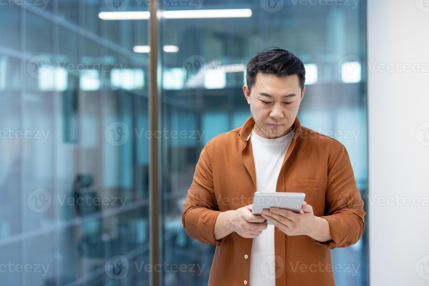 A focused programmer is seen thoughtfully interacting with a tablet device in a modern office setting. photo