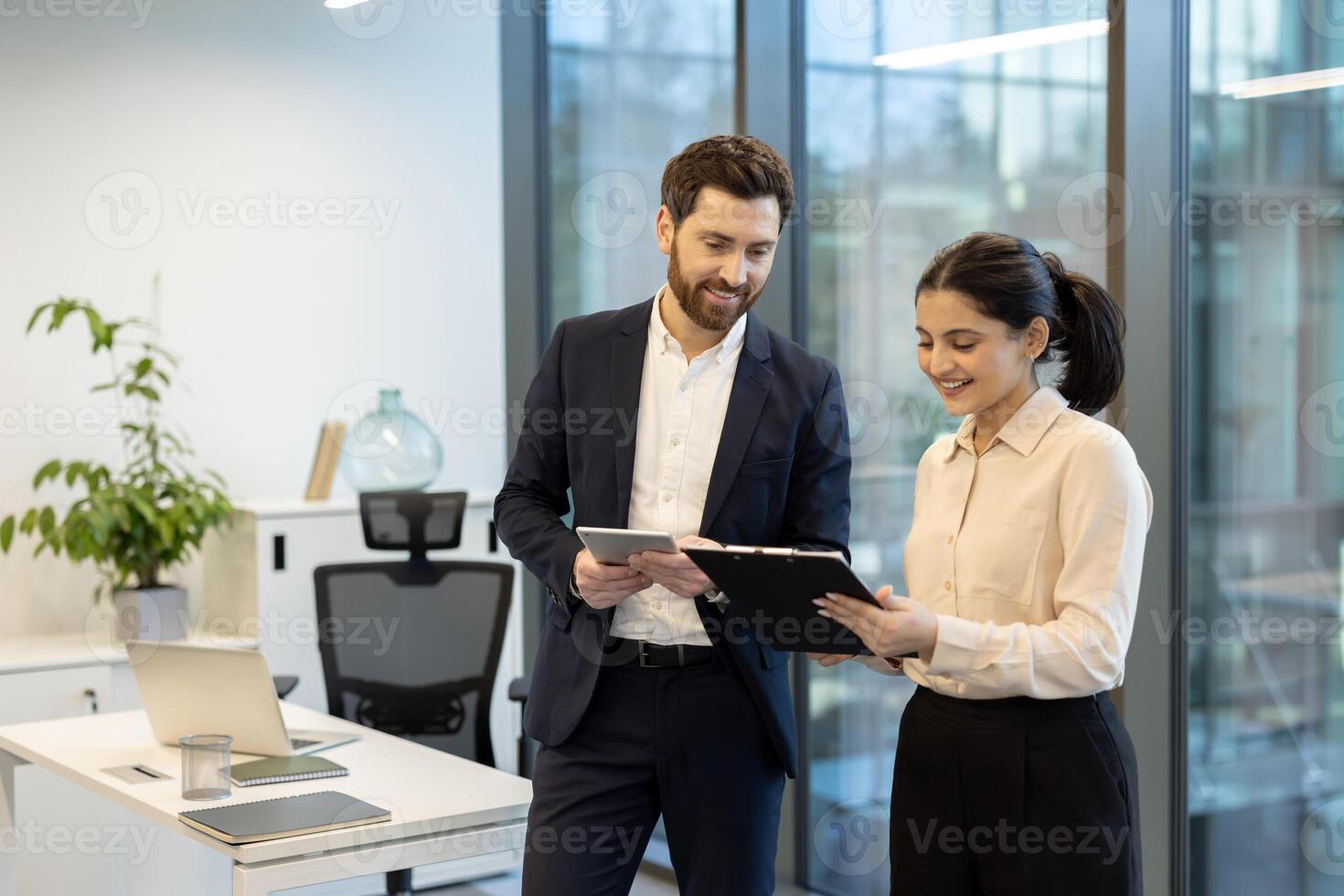 A diverse team of professionals collaborates in a modern office environment, reviewing documents and using a tablet together, creating a focused work atmosphere. photo