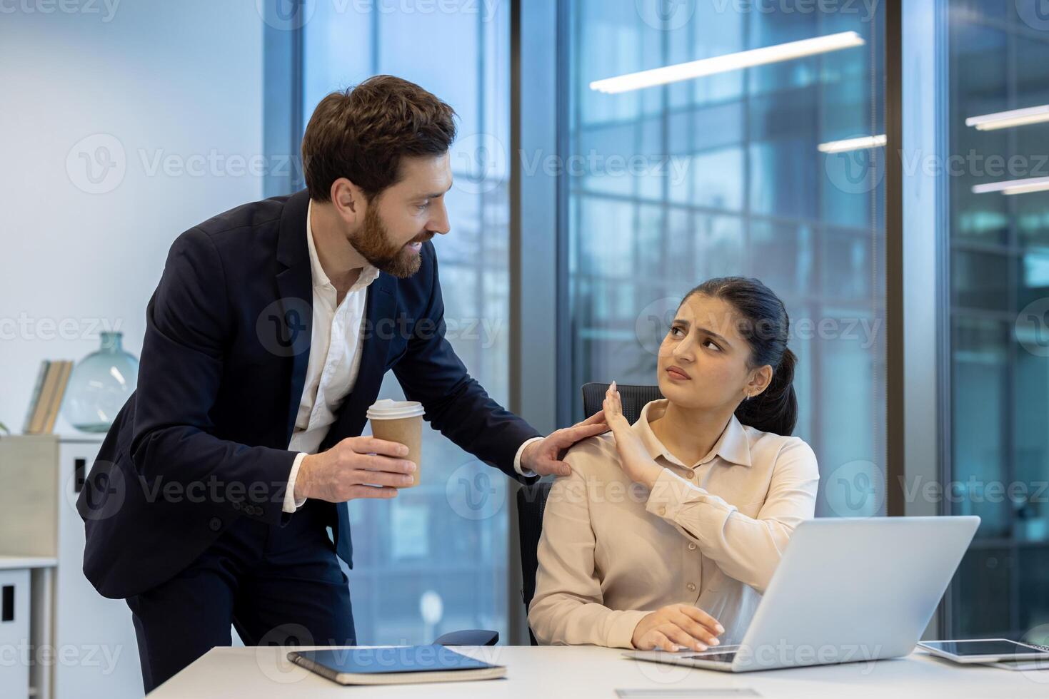 A woman at work rebuffs unwanted attention from a male colleague, conveying discomfort and rejection with body language. photo