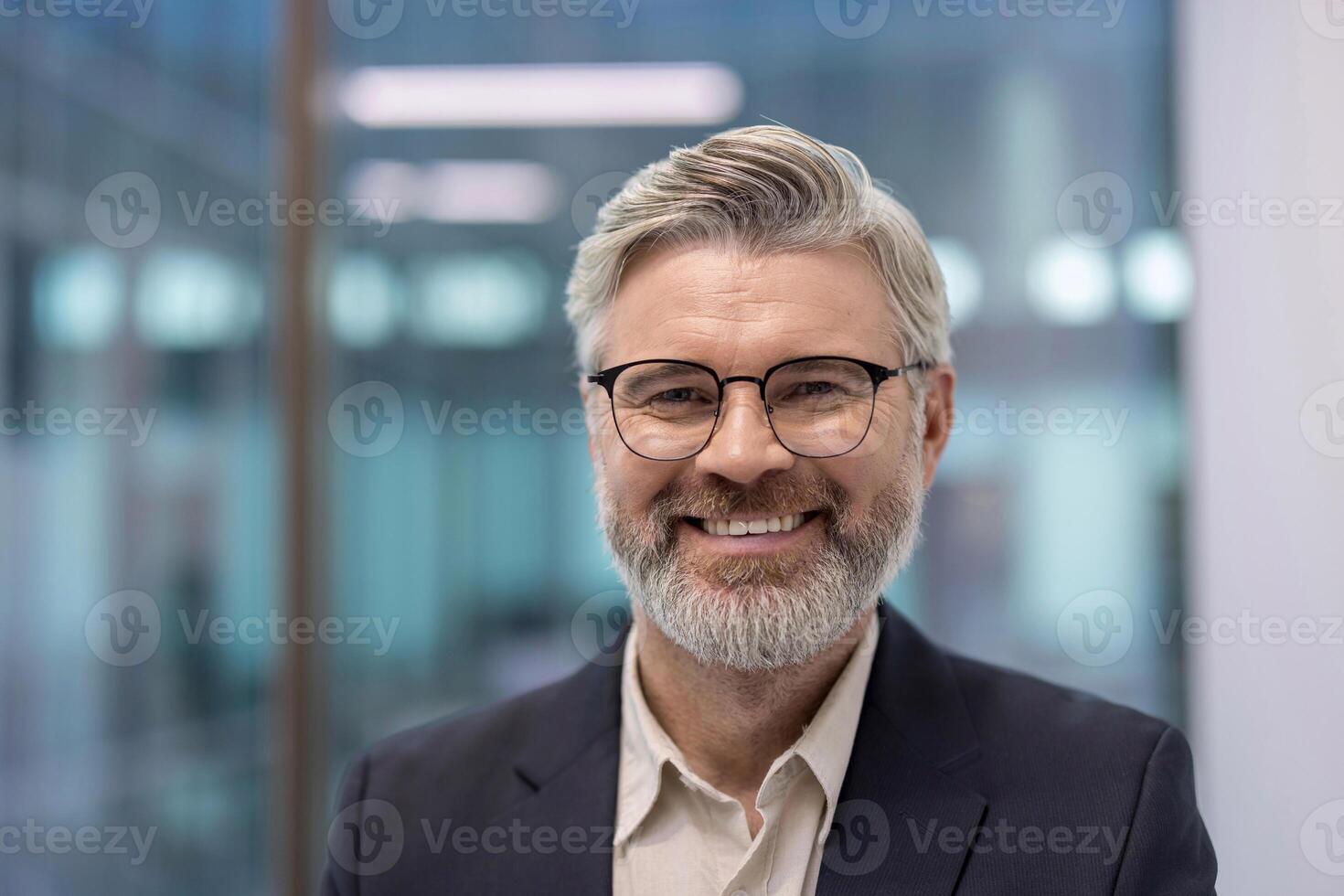 A portrait of a smiling mature businessman wearing glasses, showcasing confidence and success. The office background adds a professional atmosphere. photo