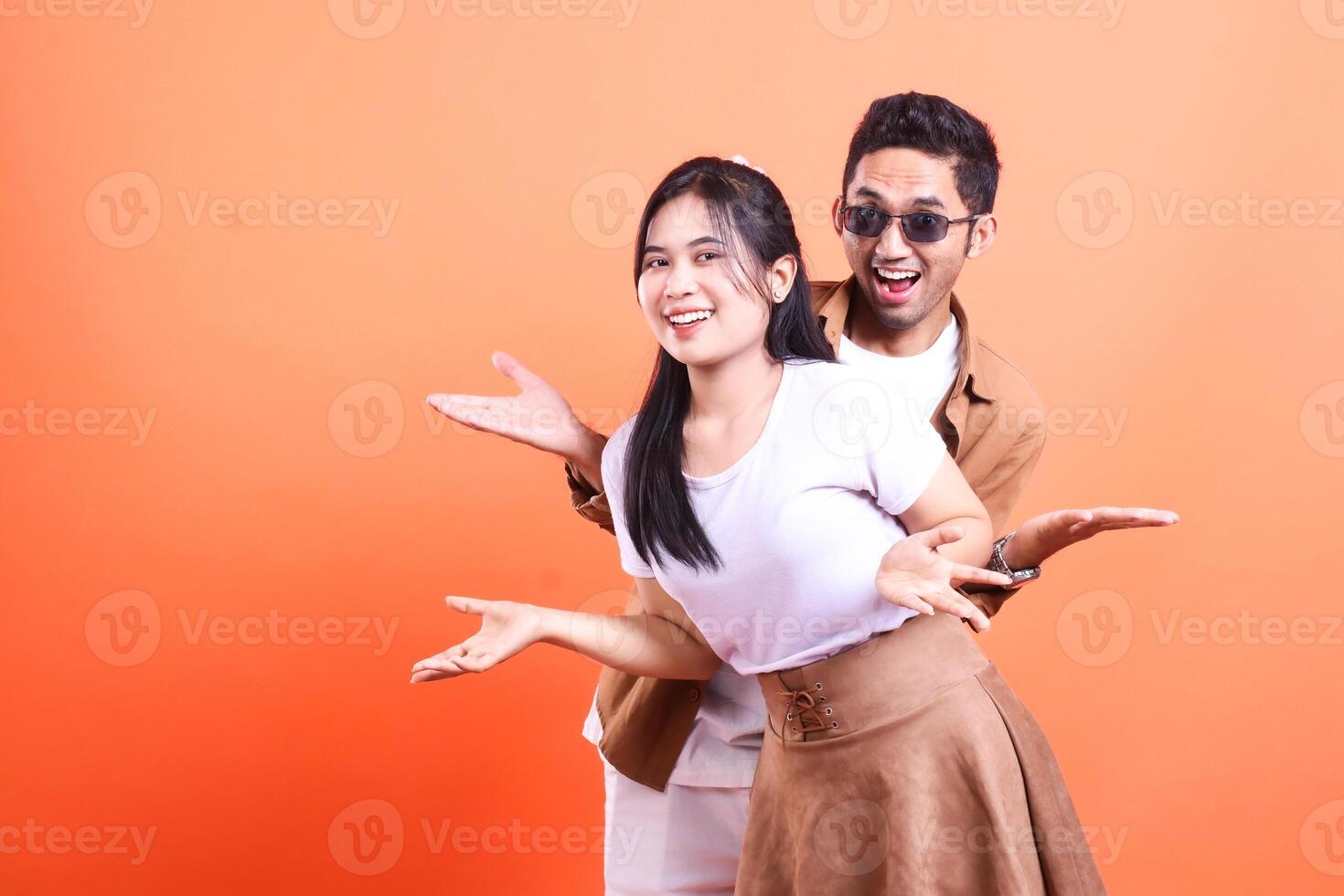 a young couple of lovers very happy expression where man and woman stand crosswise in front very romantic. isolated on orange background photo