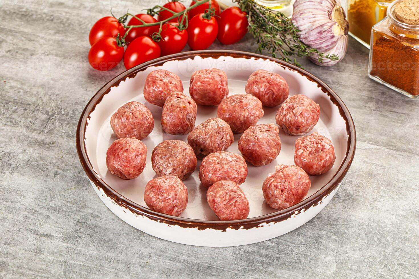 A bowl of meatballs on a table next to a bowl of tomatoes photo