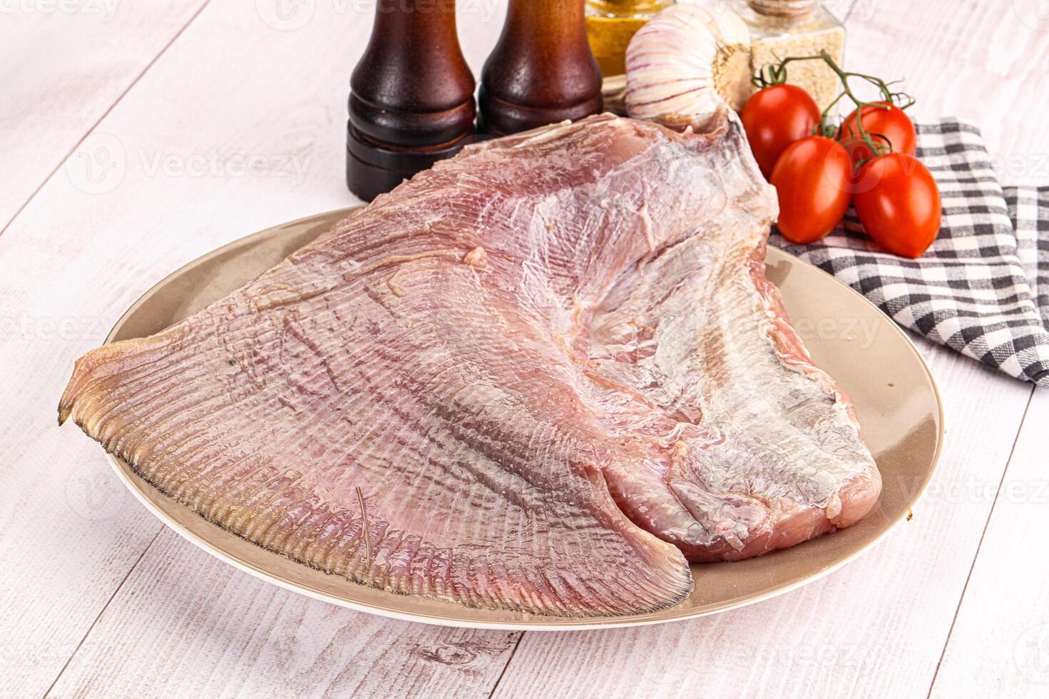 A piece of raw fish on a plate with a knife and other ingredients photo