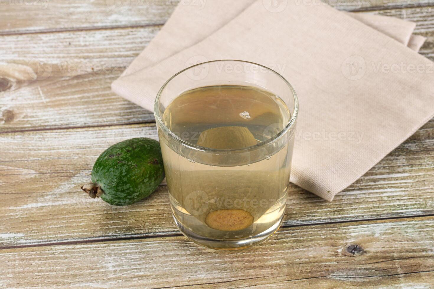 A glass of liquid with an avocado on a wooden table photo