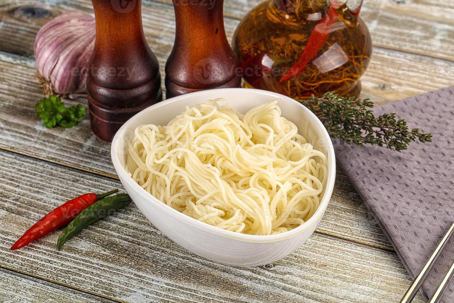 A bowl of noodles, chopsticks and a bottle of vinegar photo