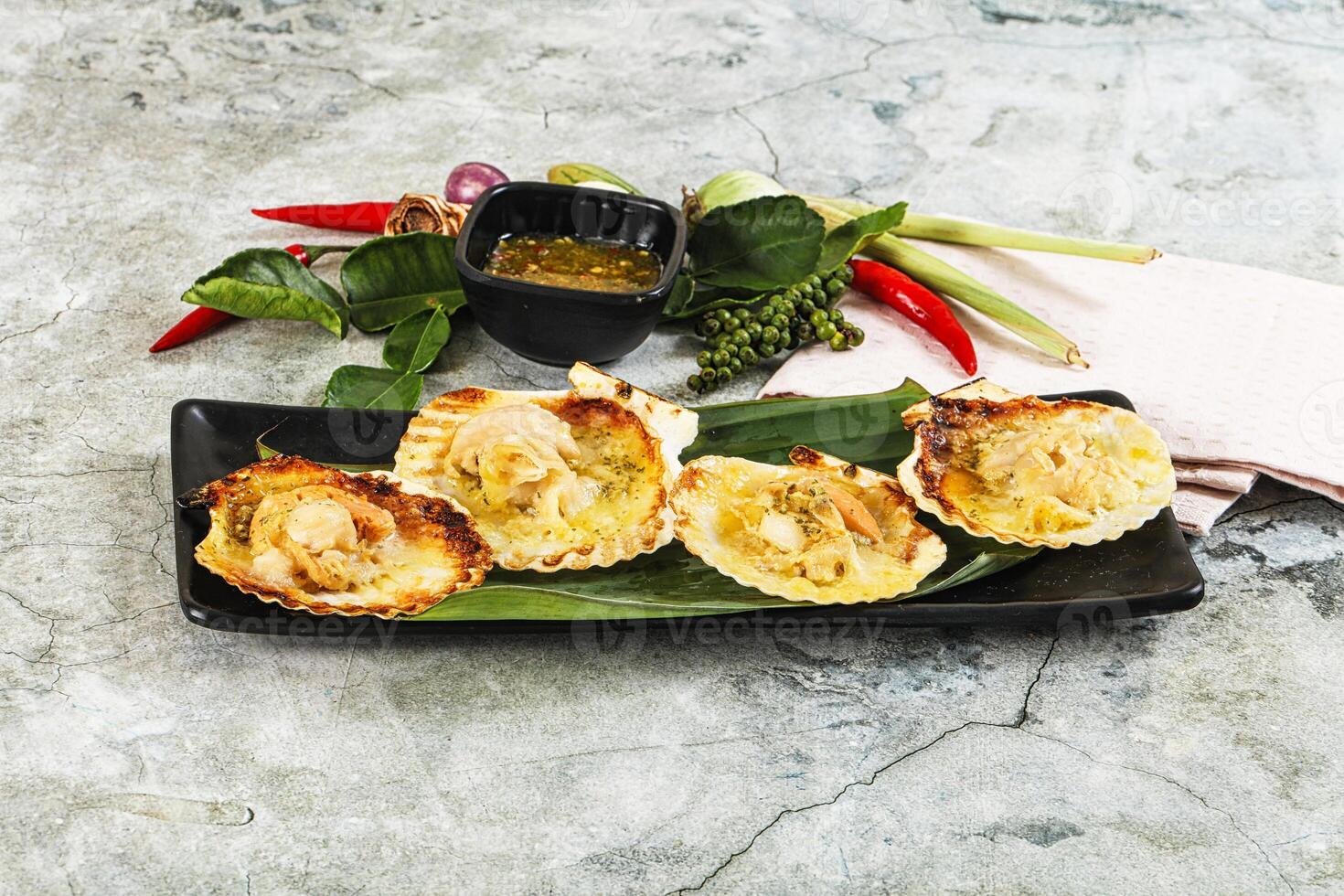 Three scallops on a black plate with sauce photo