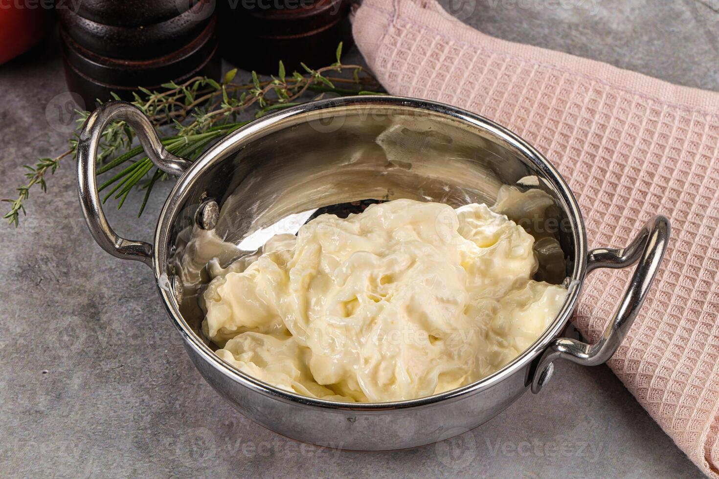 A metal bowl filled with butter next to a towel photo
