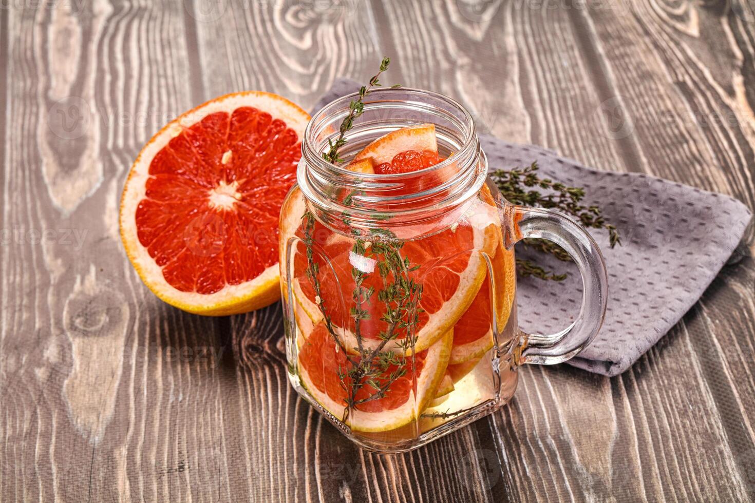 A glass jar filled with grapefruit slices and herbs photo