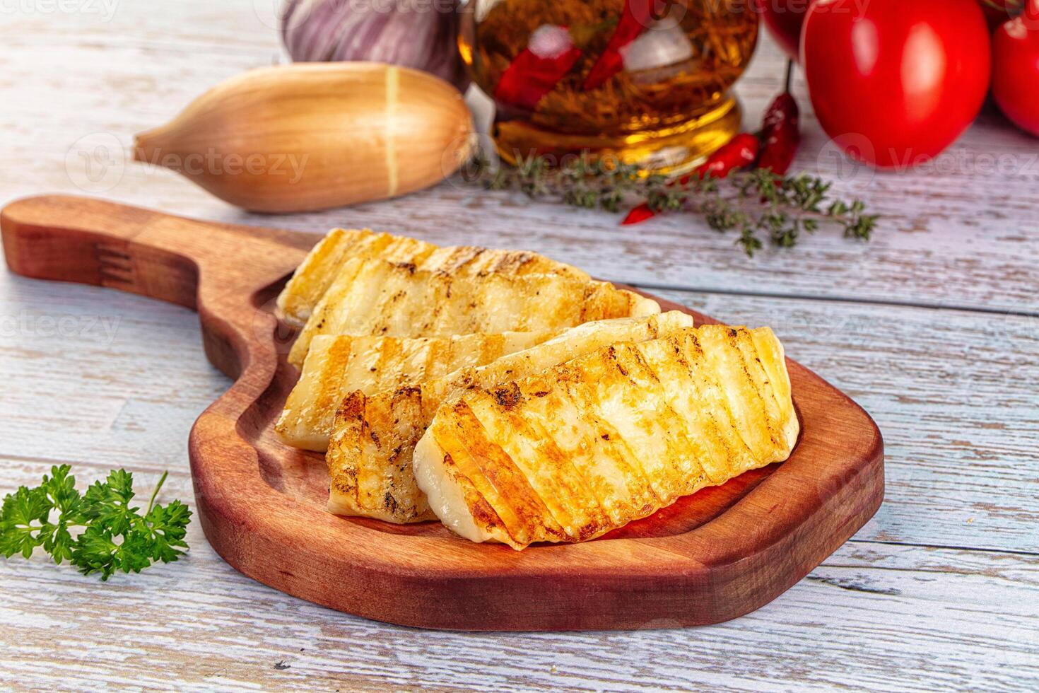 A wooden cutting board with some vegetables and garlic photo