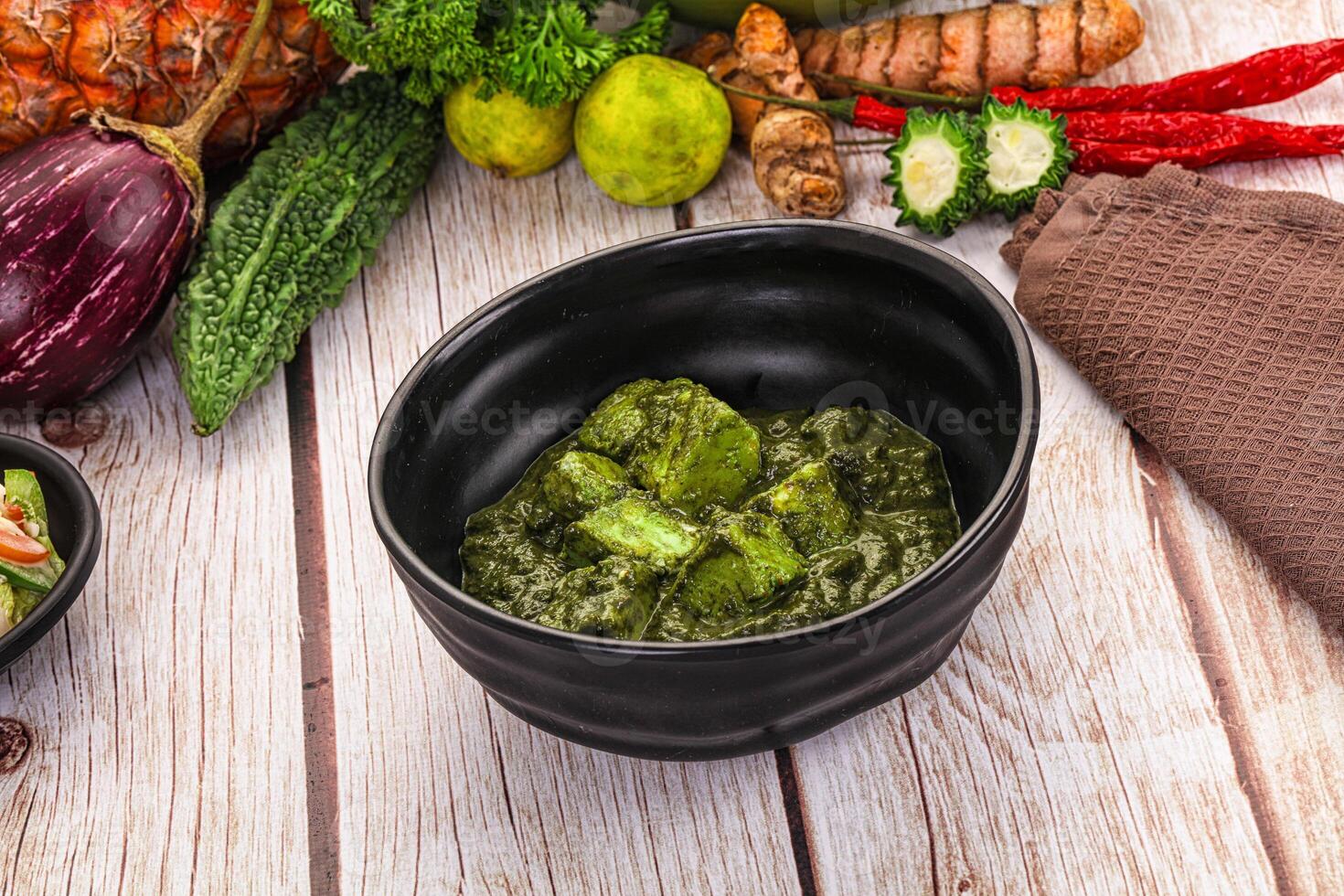 A bowl of green curry with vegetables and spices photo