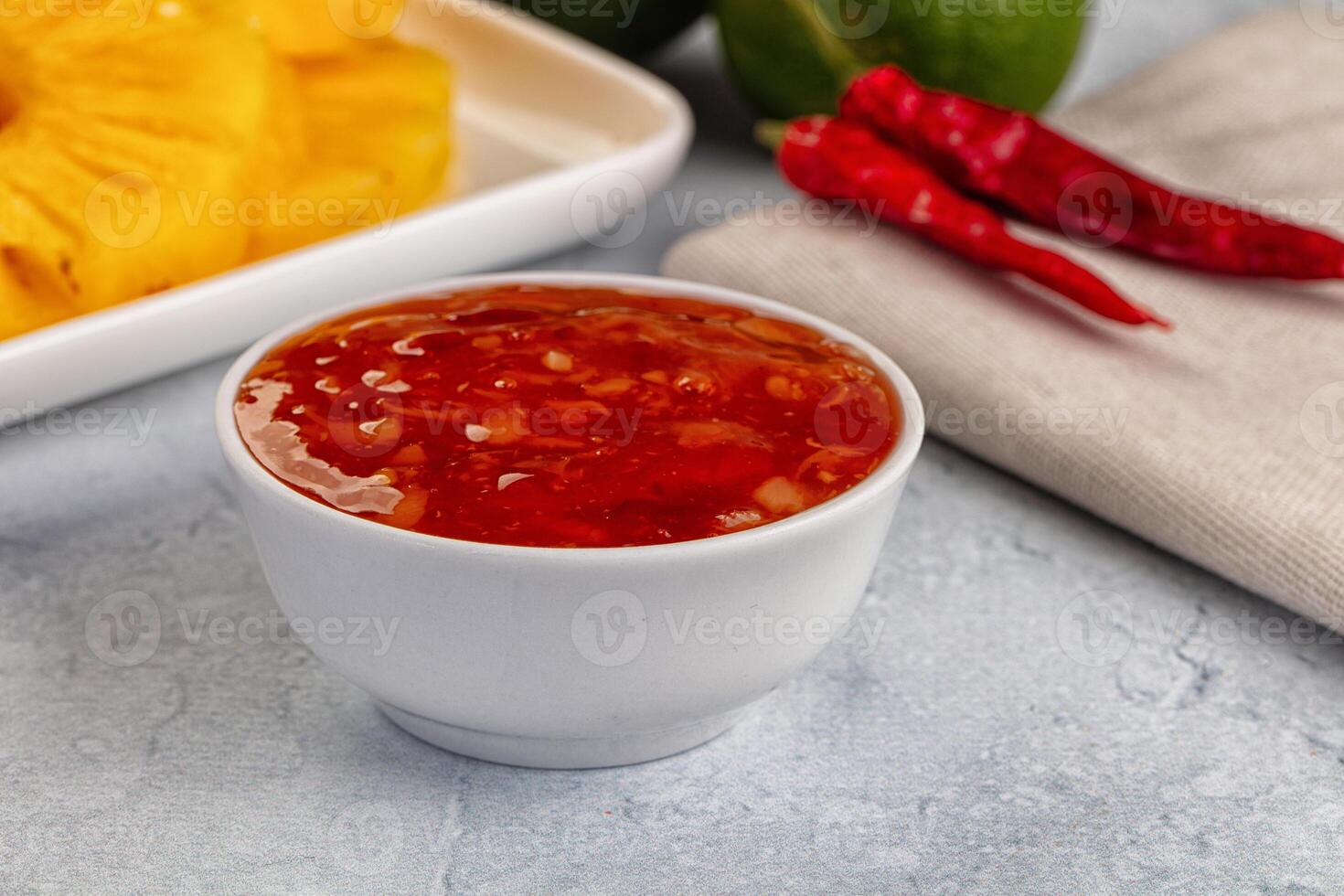 A bowl of sauce next to a plate of pineapple photo