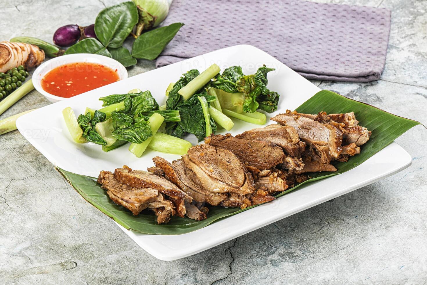 A plate with meat, vegetables and sauce on it photo