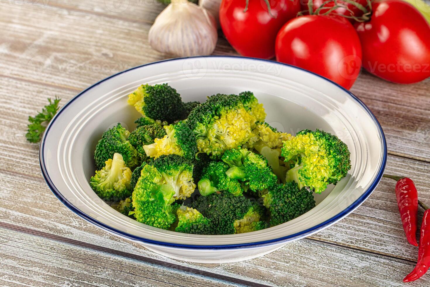 A bowl of broccoli with tomatoes and peppers on a table photo