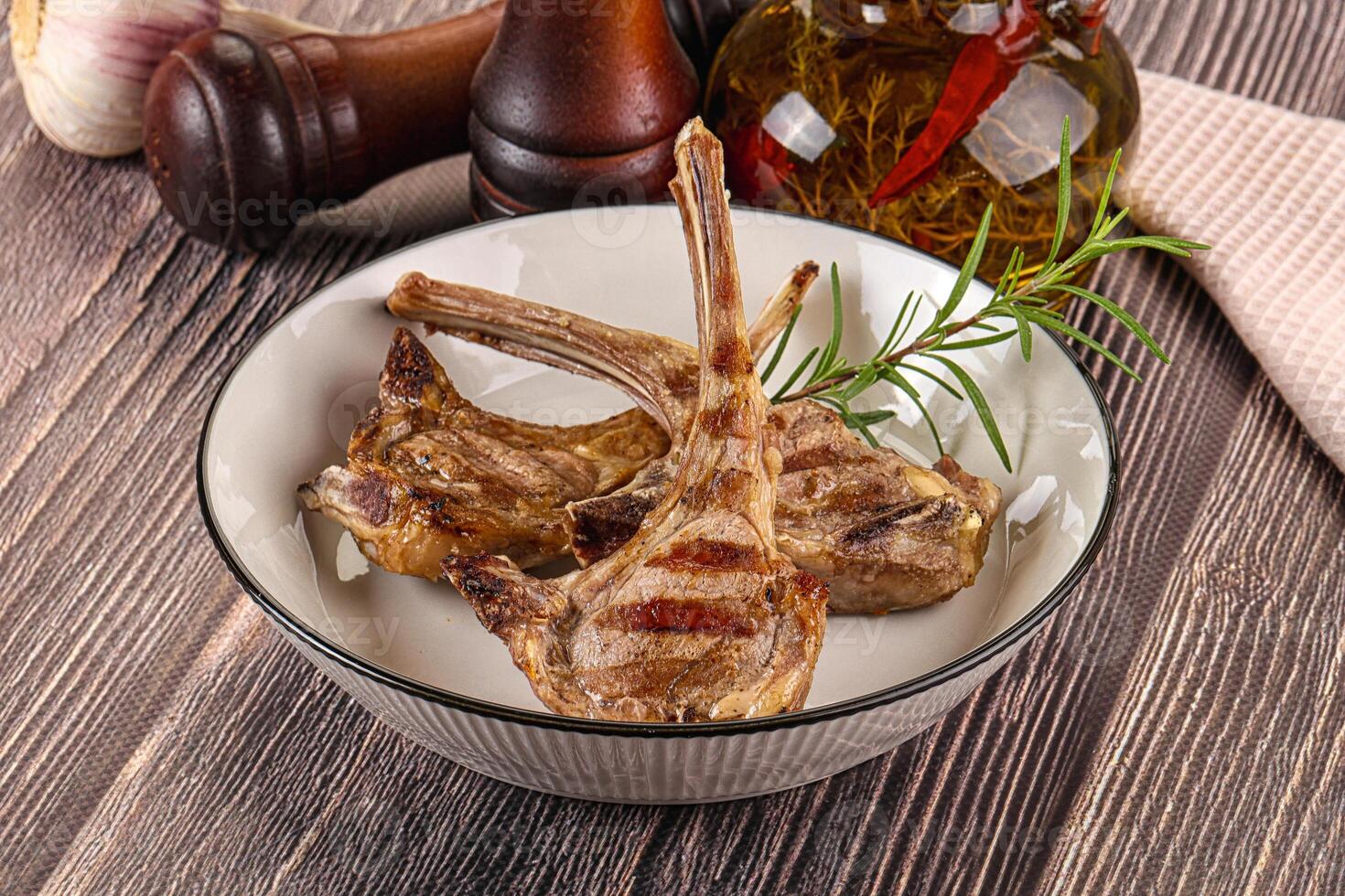 A bowl of meat with garlic and herbs on a wooden table photo