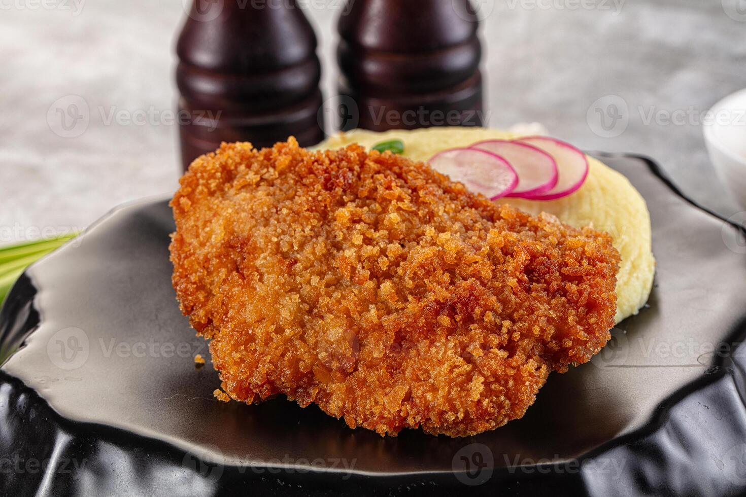 Fried chicken with rice and pickles on a black plate photo