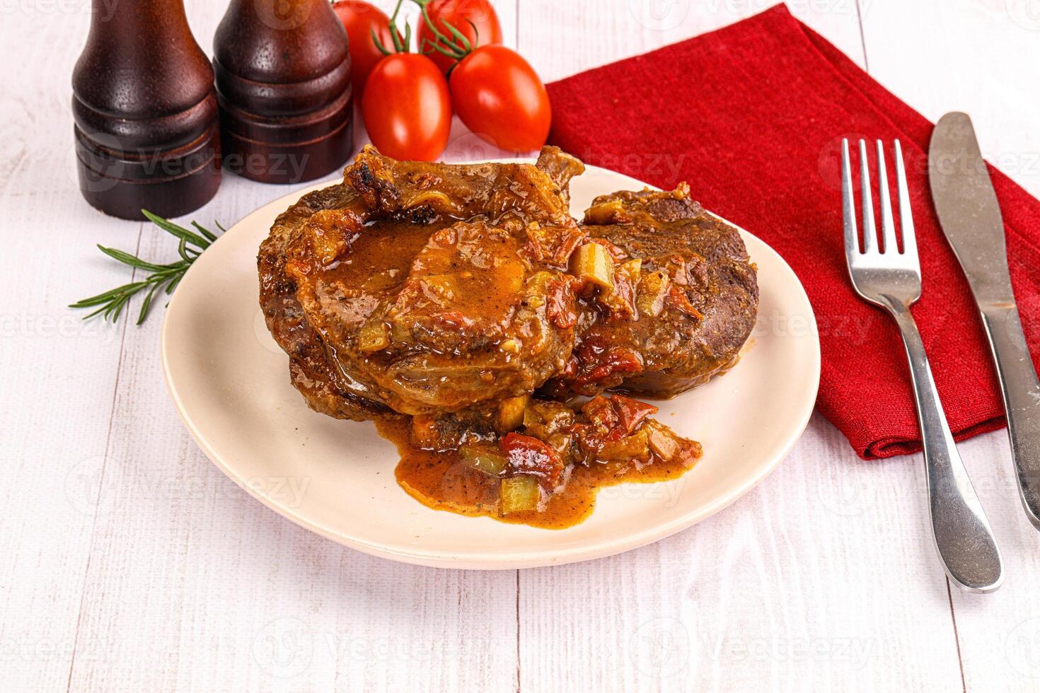 A plate of meat with gravy and tomatoes on a table photo