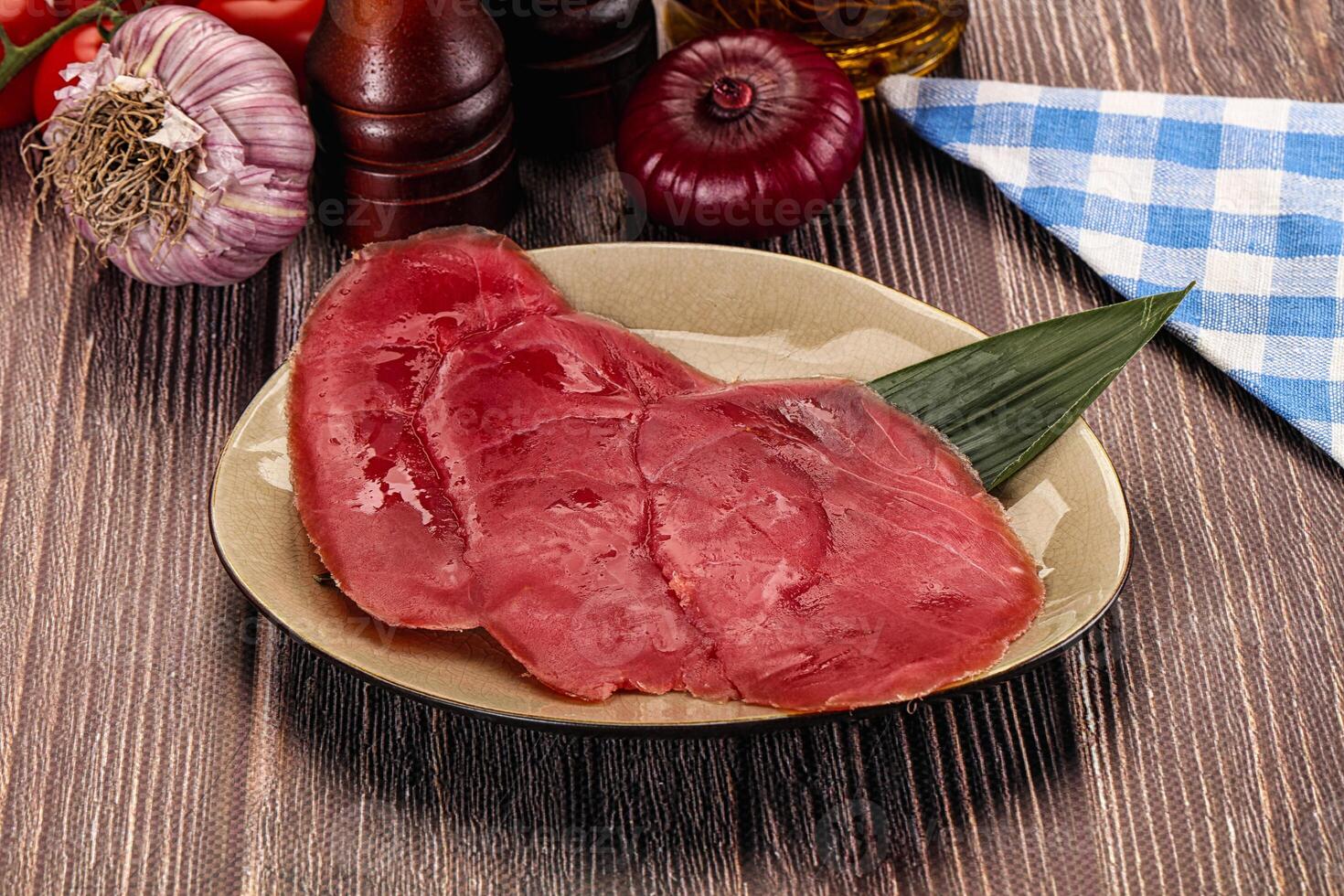 A plate of raw meat on a table with other ingredients photo