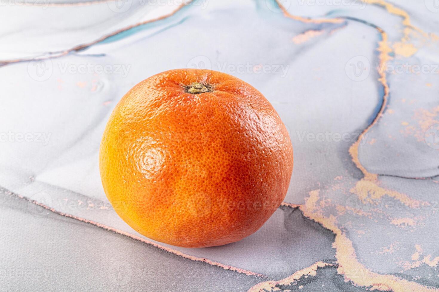 A close up of an orange on a marble surface photo