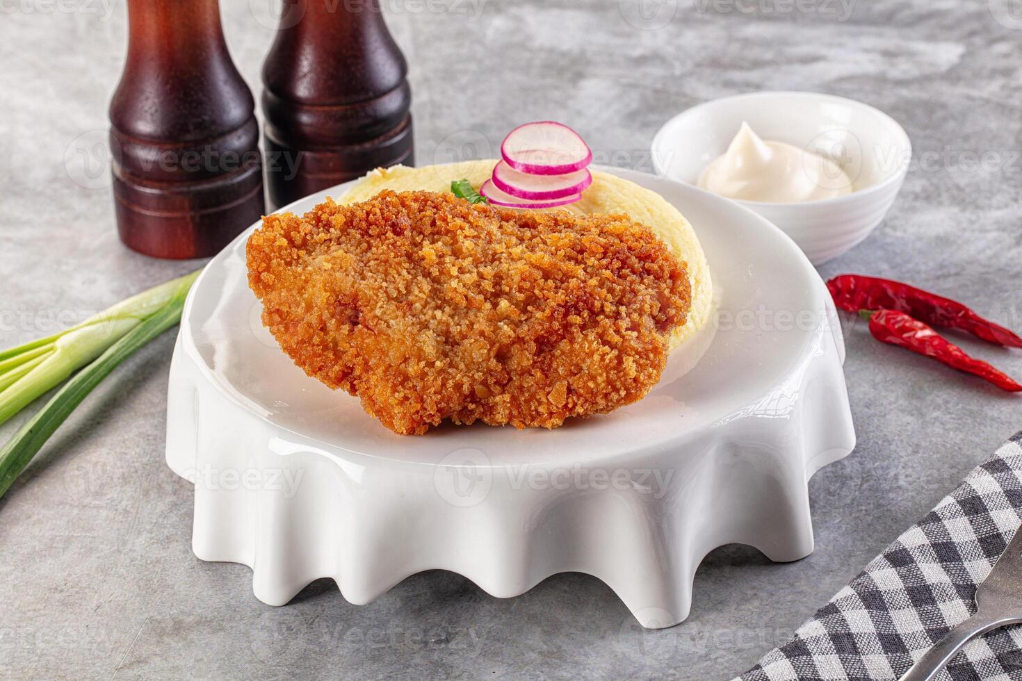 Fried chicken cutlet on white plate with sauce and vegetables photo