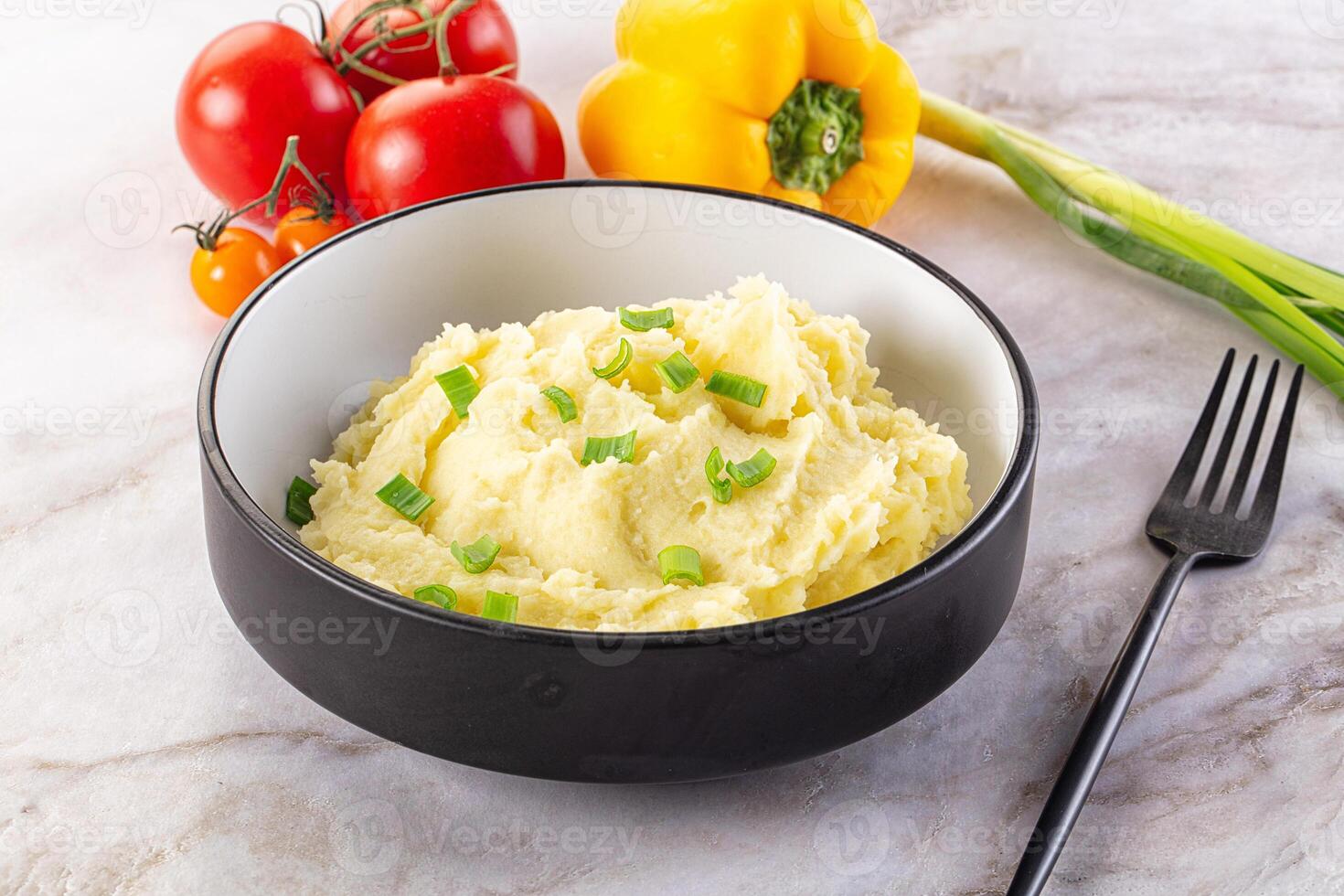 A bowl of mashed potatoes with green onions and tomatoes photo