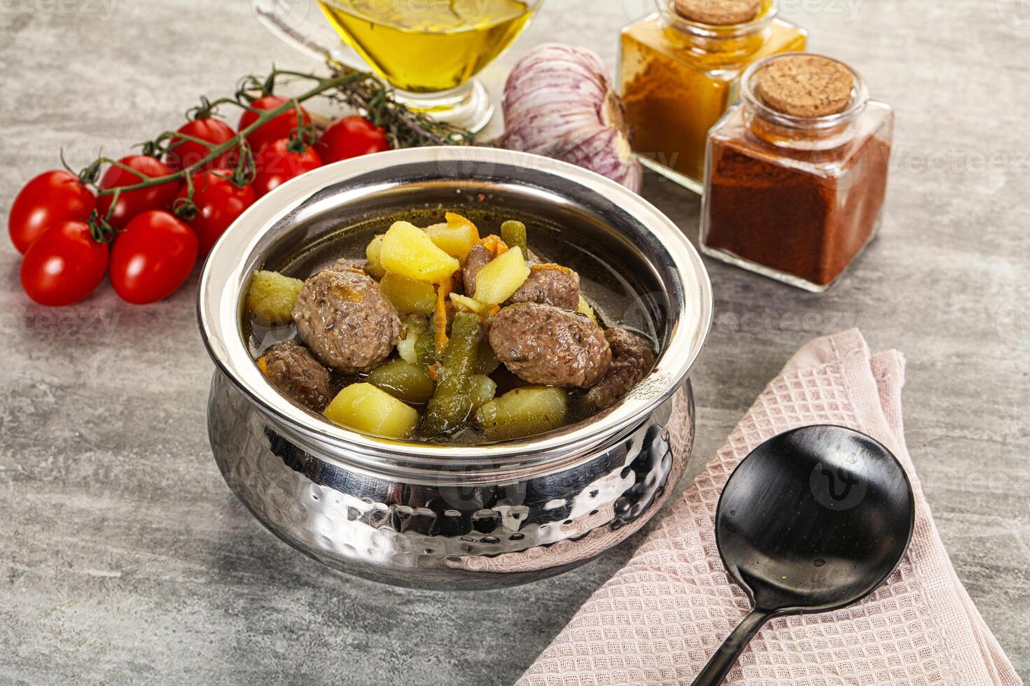 A silver bowl filled with food and a spoon photo