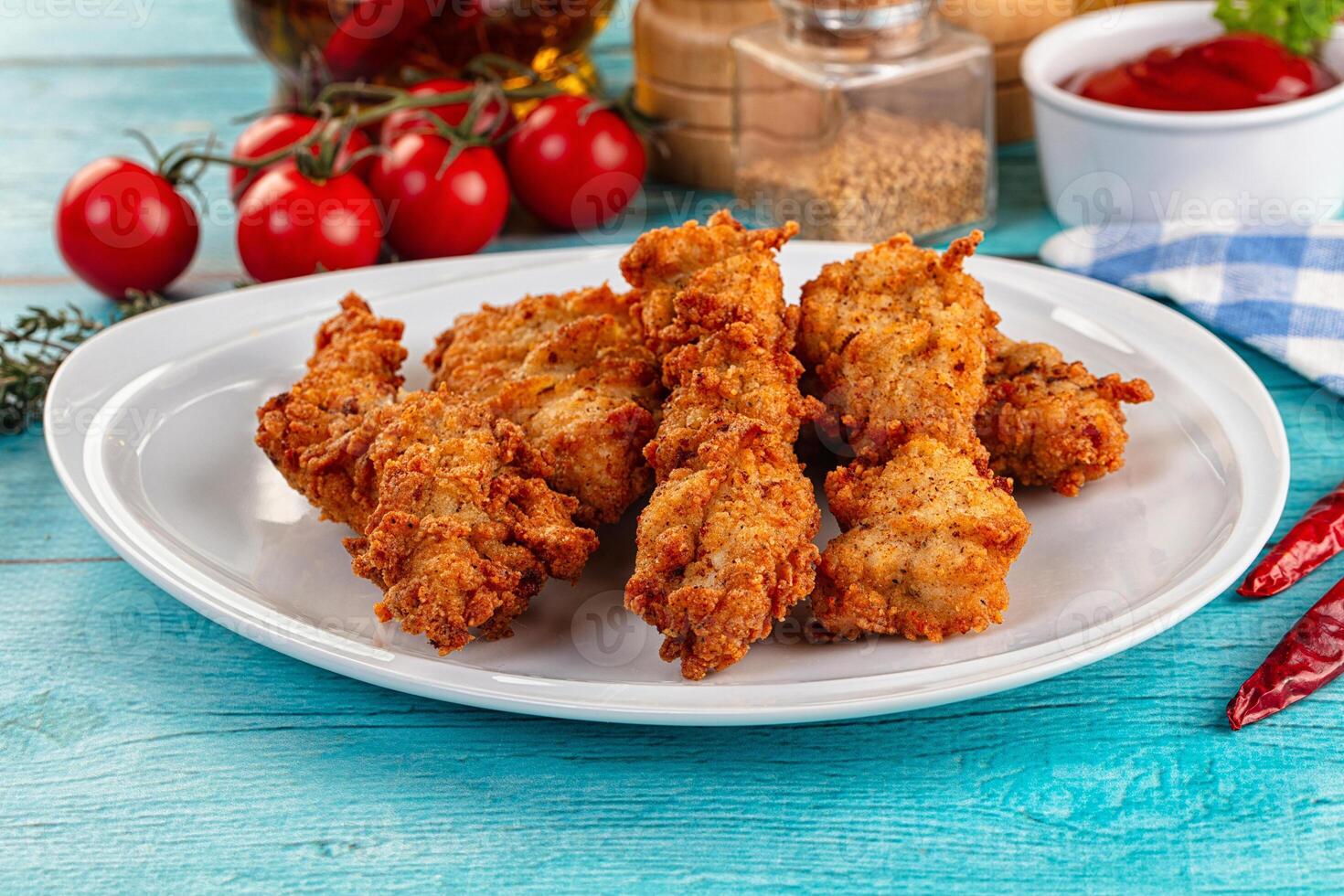 Fried chicken wings on a white plate with sauce and tomatoes photo
