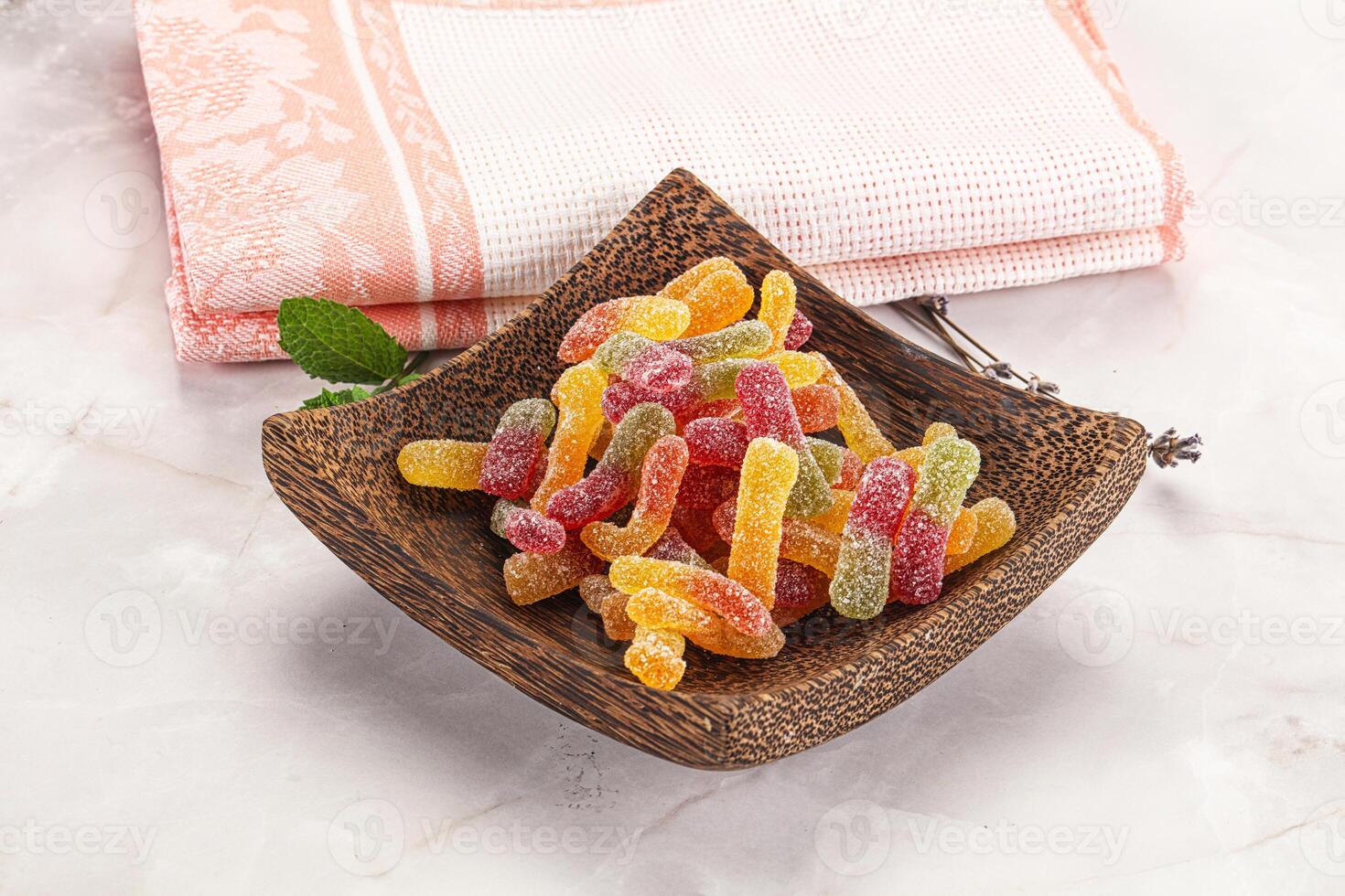 A wooden bowl with a bowl of gummy worms photo
