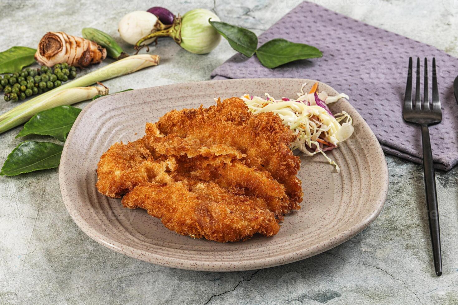 A plate with fried chicken and vegetables on a table photo
