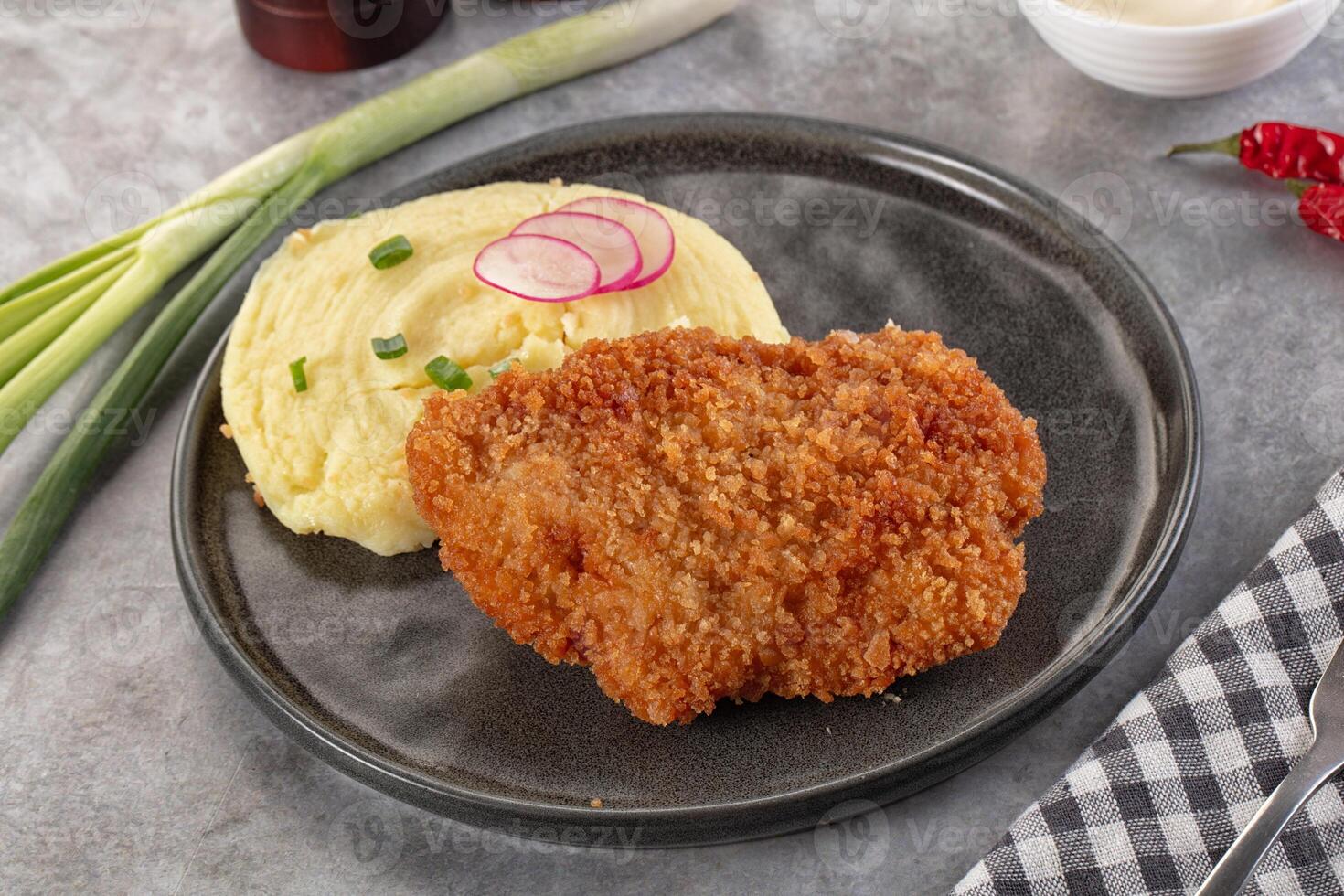 A plate with a piece of meat and mashed potatoes photo