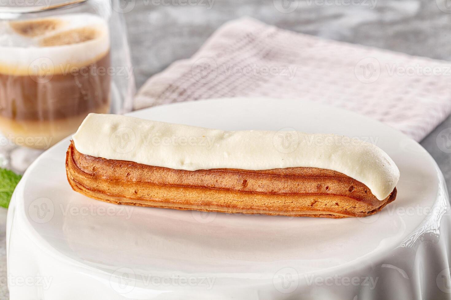 A pastry on a plate with a drink next to it photo