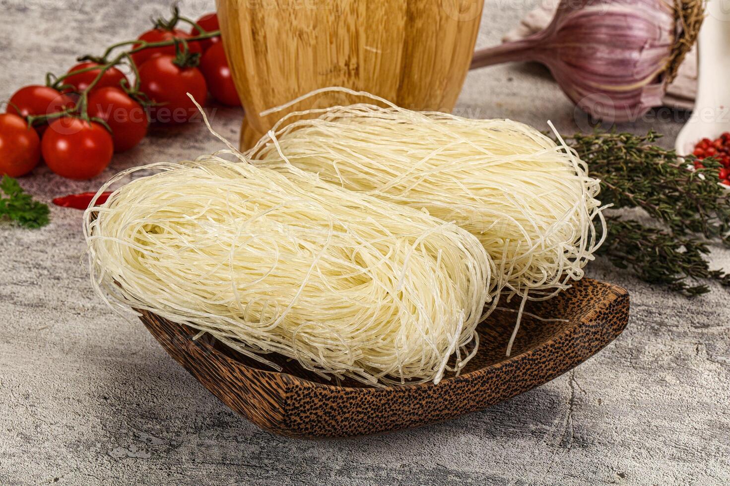 A bowl of noodles, garlic, and tomatoes on a table photo