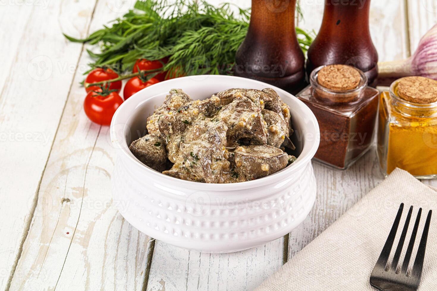 A white bowl of meat with vegetables and condiments photo