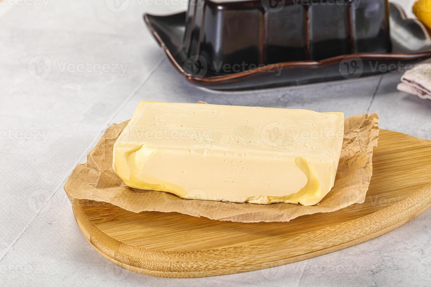 A butter block on a cutting board next to a bowl of lemons photo