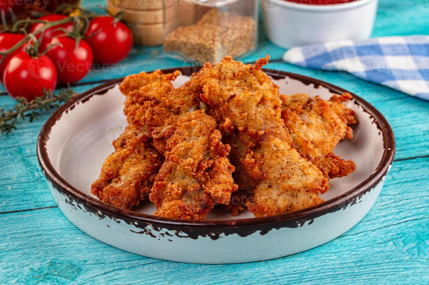 Fried chicken nuggets in a white bowl on a blue table photo