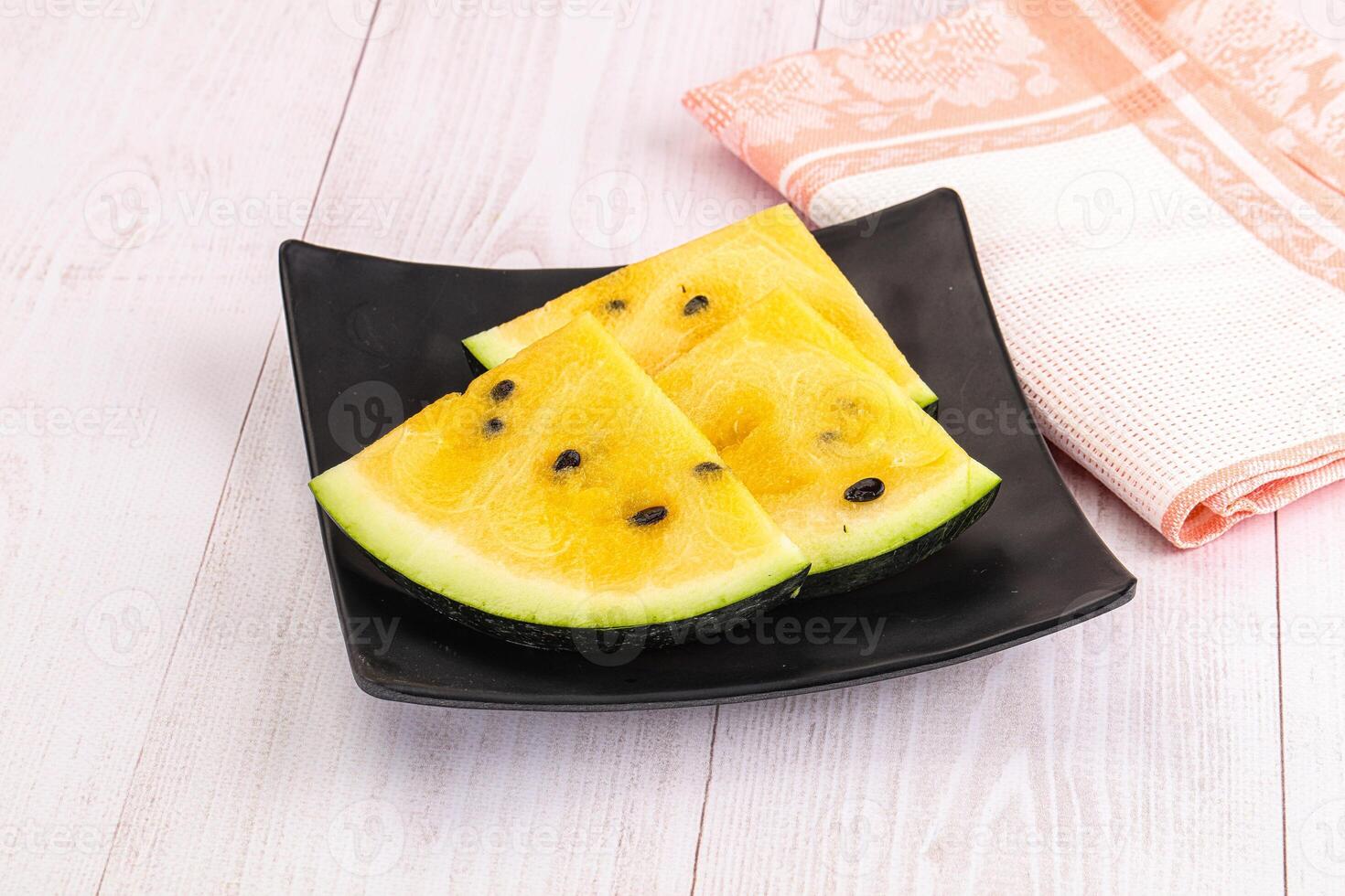 A black plate with slices of yellow and black melon photo