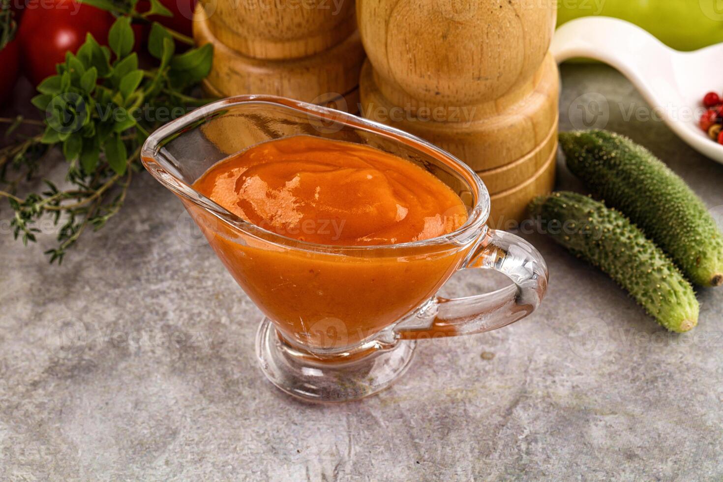 A glass of tomato sauce next to a pepper and cucumber photo
