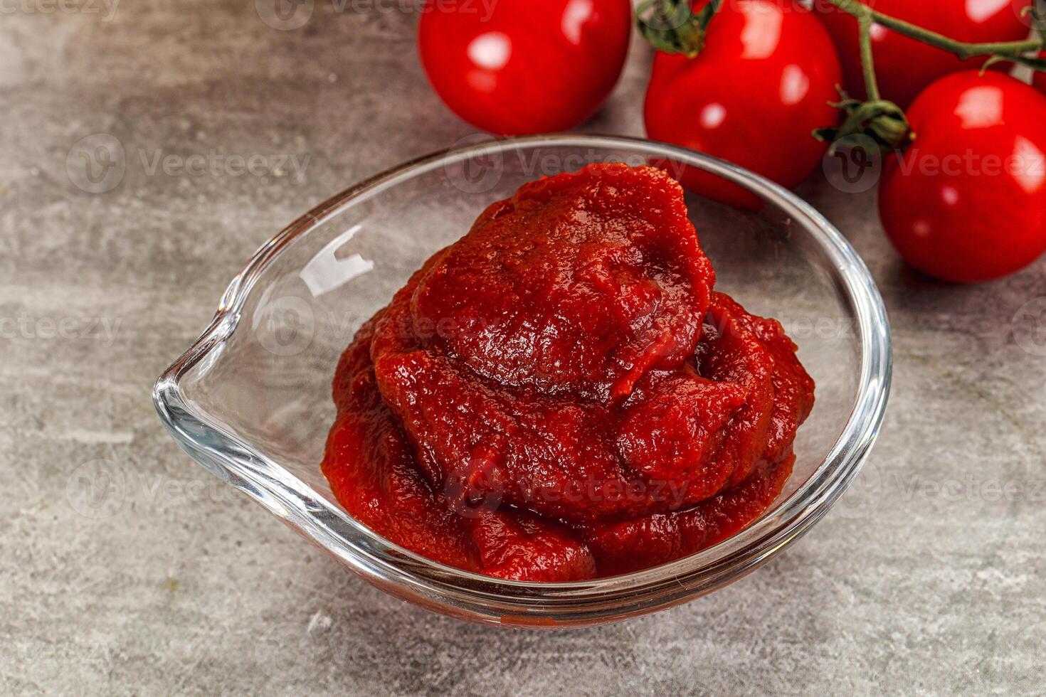 A bowl of tomato sauce next to some tomatoes photo