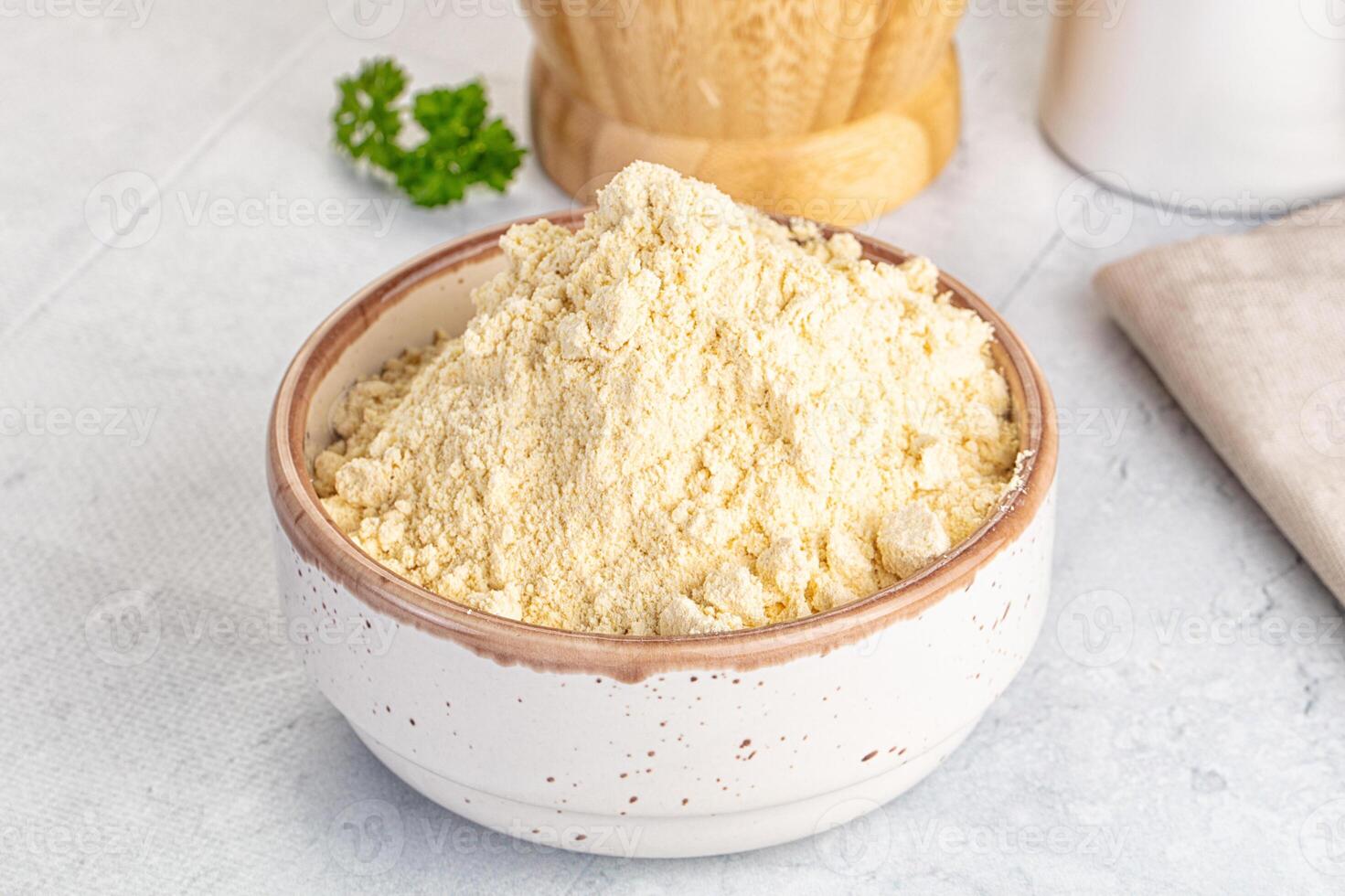 A bowl of flour and a wooden spoon next to a wooden bowl photo