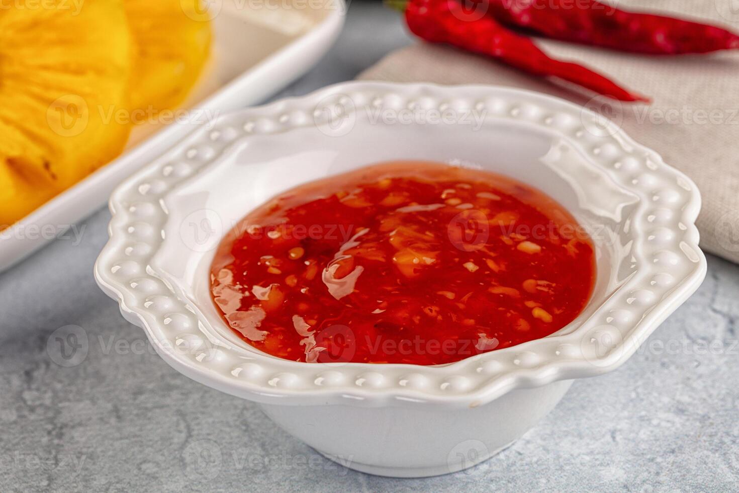 A bowl of chili sauce next to a bowl of corn photo