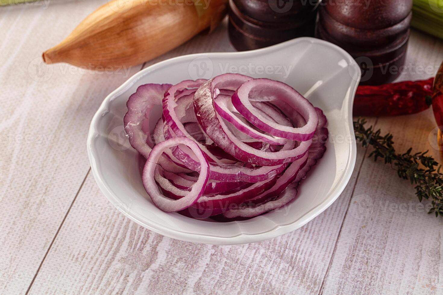 A bowl of sliced onions on a table next to other ingredients photo