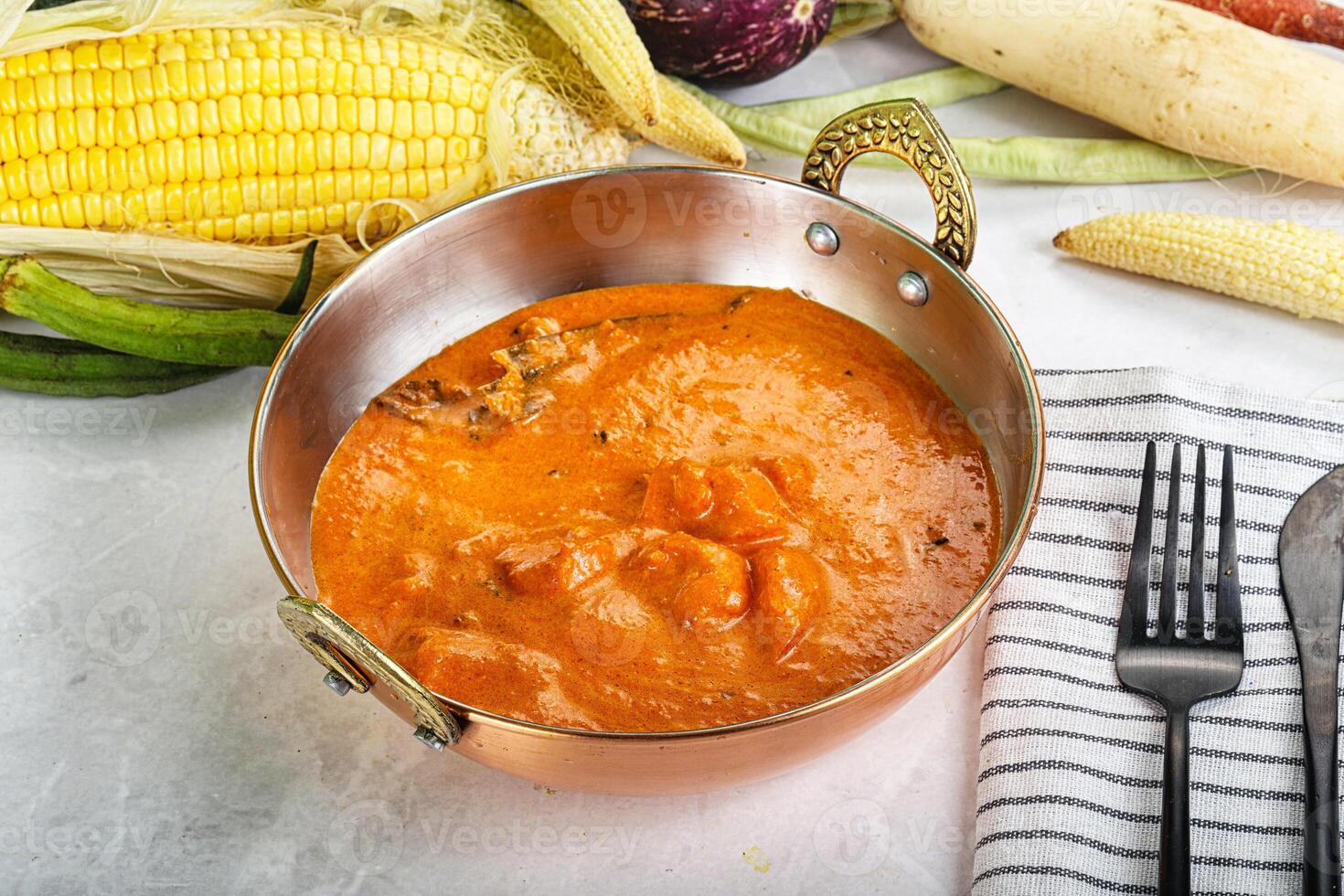 A bowl of soup next to a plate of corn and a knife photo