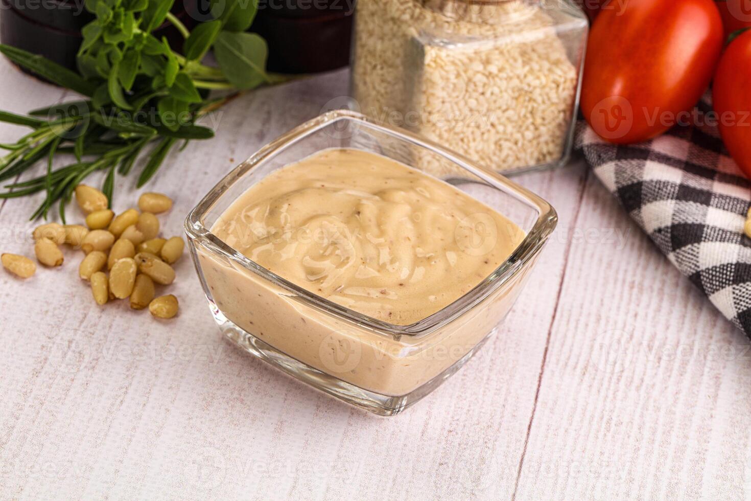 A glass container with a bowl of dressing next to tomatoes, garlic and other ingredients photo