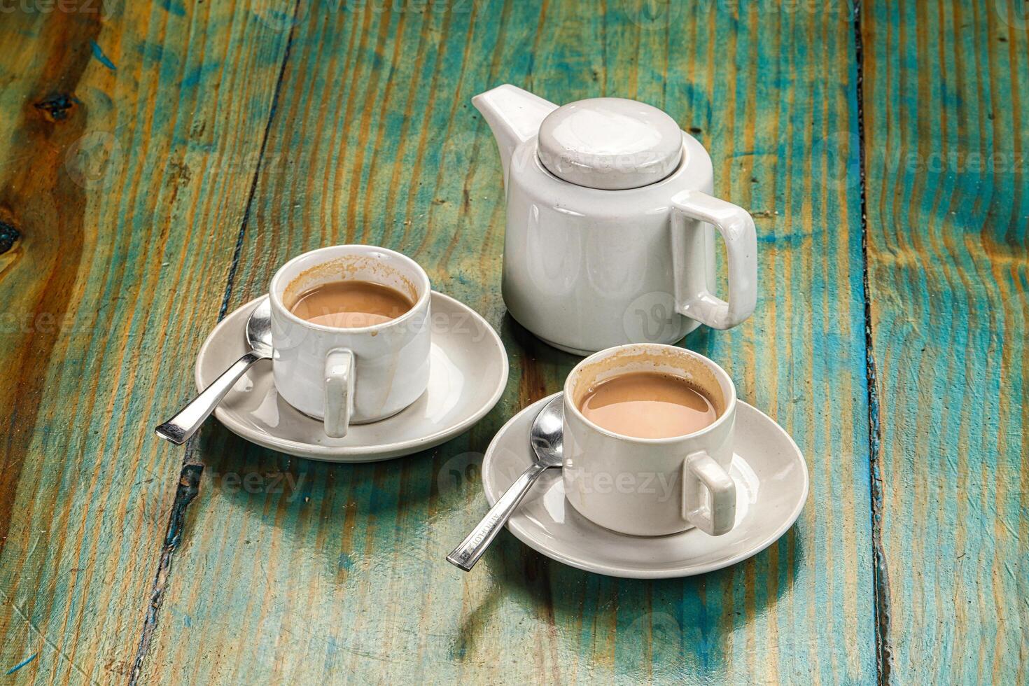 A table with two cups of coffee and a teapot photo