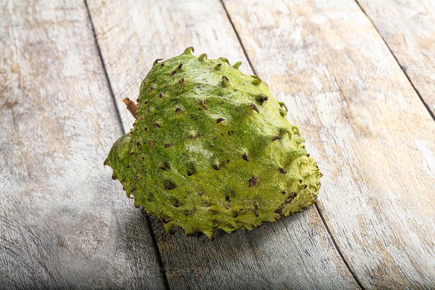 A single fruit sitting on a wooden surface photo