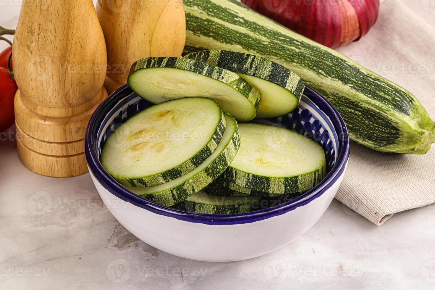 A bowl of sliced cucumbers and tomatoes on a counter photo