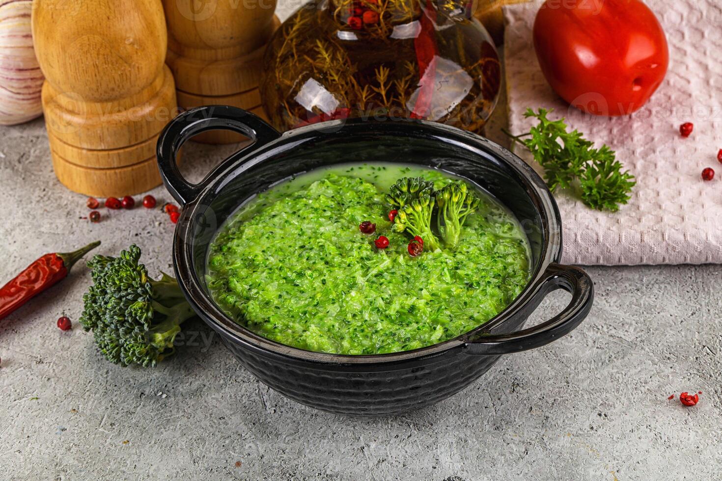 A bowl of broccoli soup with a pepper and a knife photo